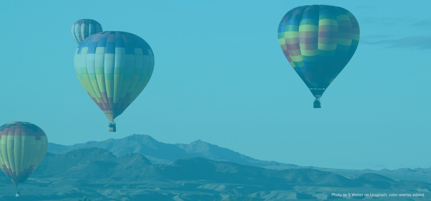 Four hot air balloons floating over the Arizona desert landscape